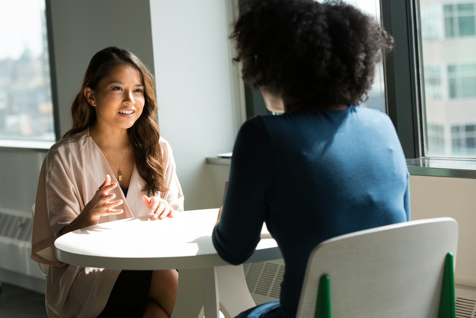 Two professionals having a thoughtful one-to-one conversation in a bright office